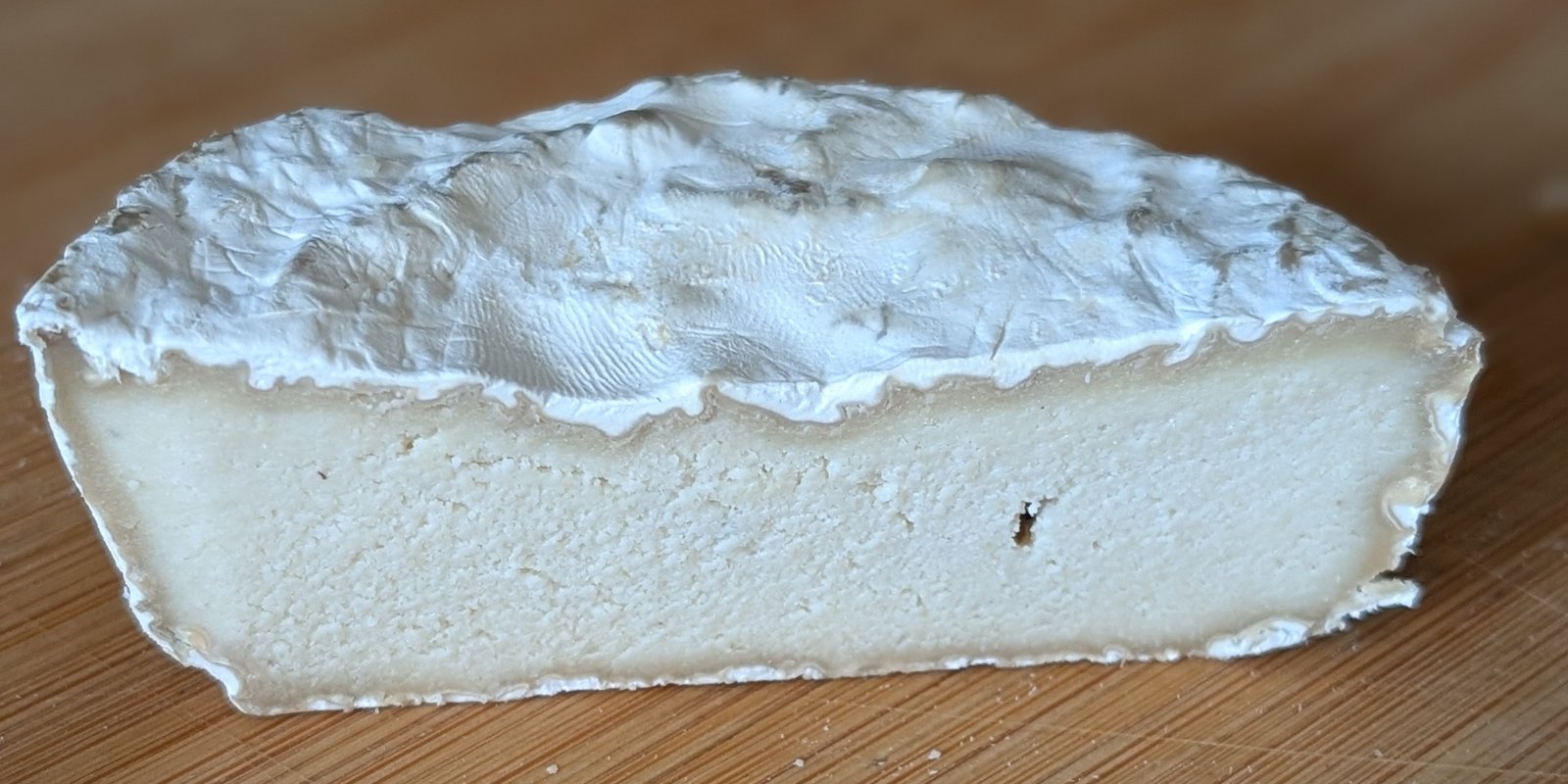 Selbstgemachter veganer Camembert aus Cashews, angeschnitten, mit weißer Schimmelrinde